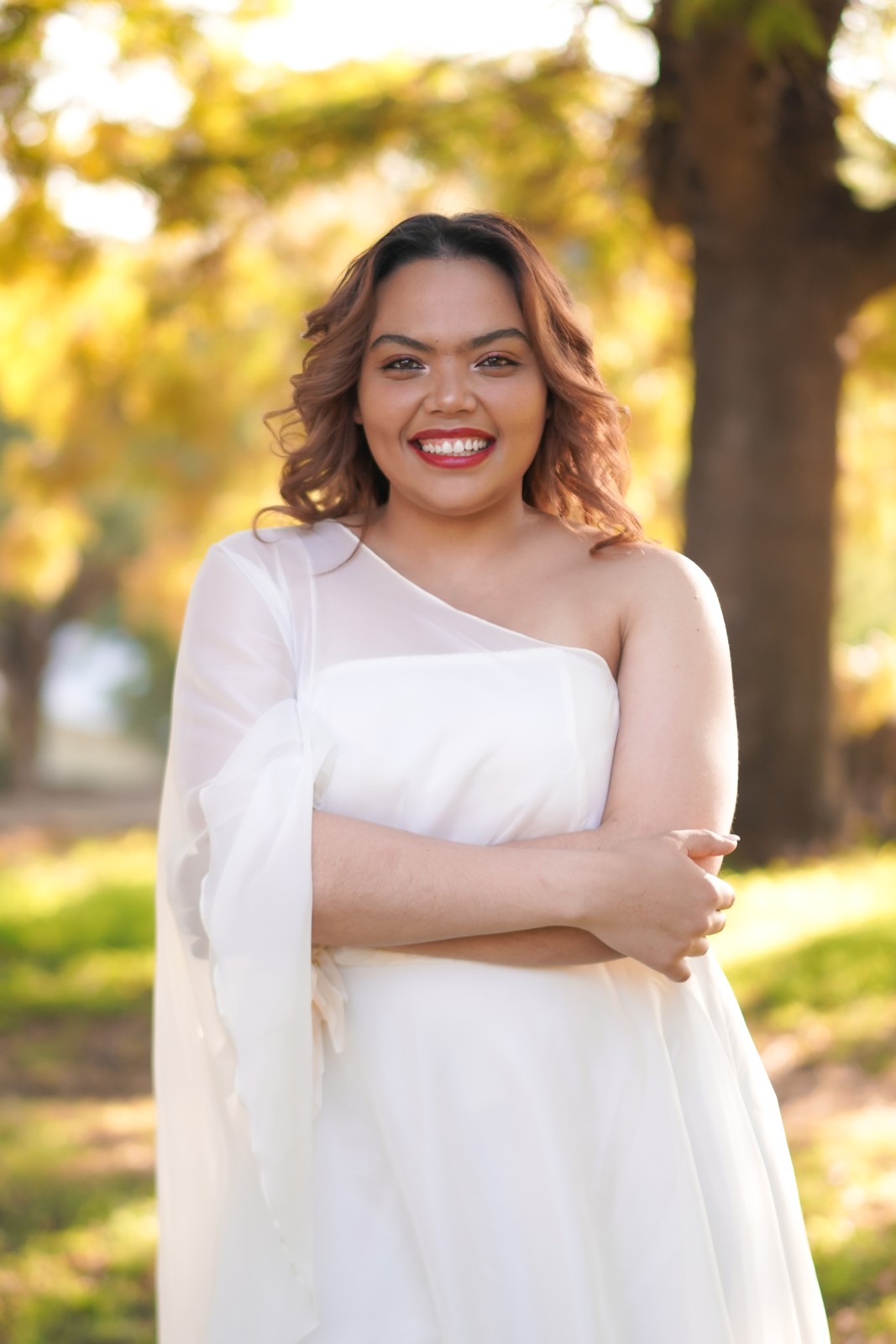 Portrait of Michelle smiling beneath sunlit trees