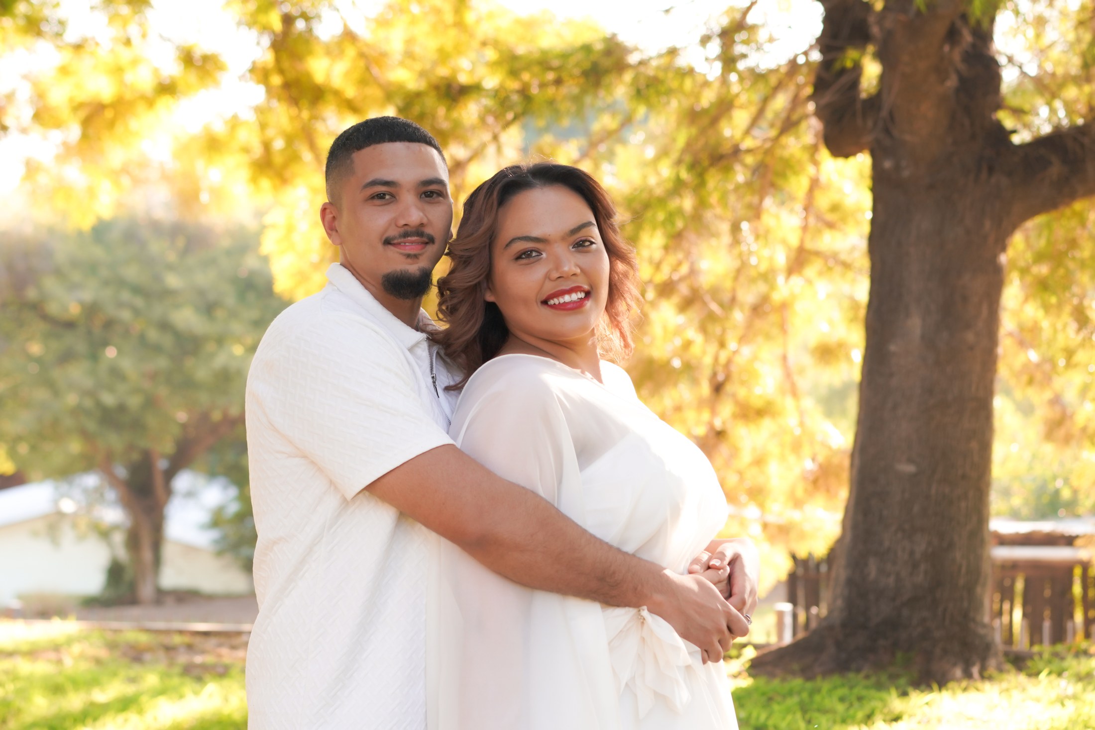 Patrick and Michelle embracing beneath sunlit trees
